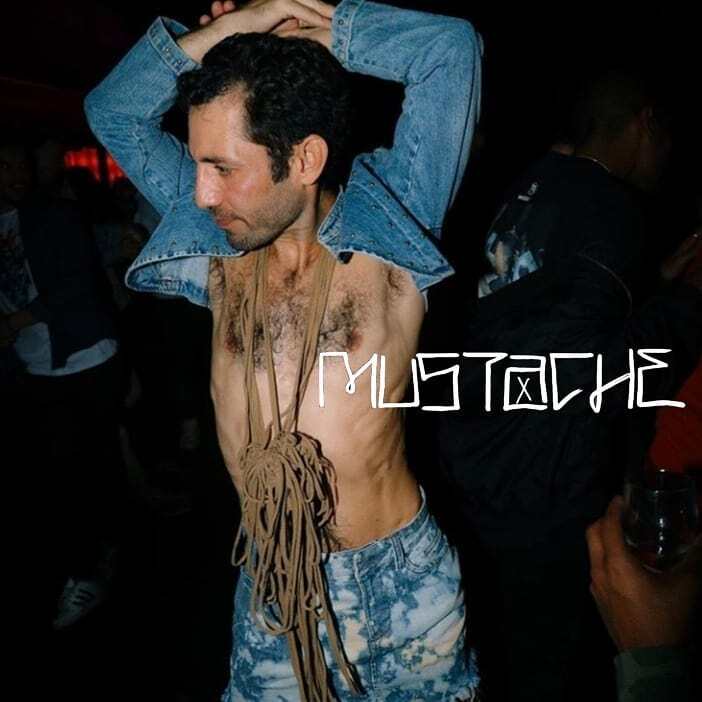 A person in a cropped denim jacket and a rope necklace.