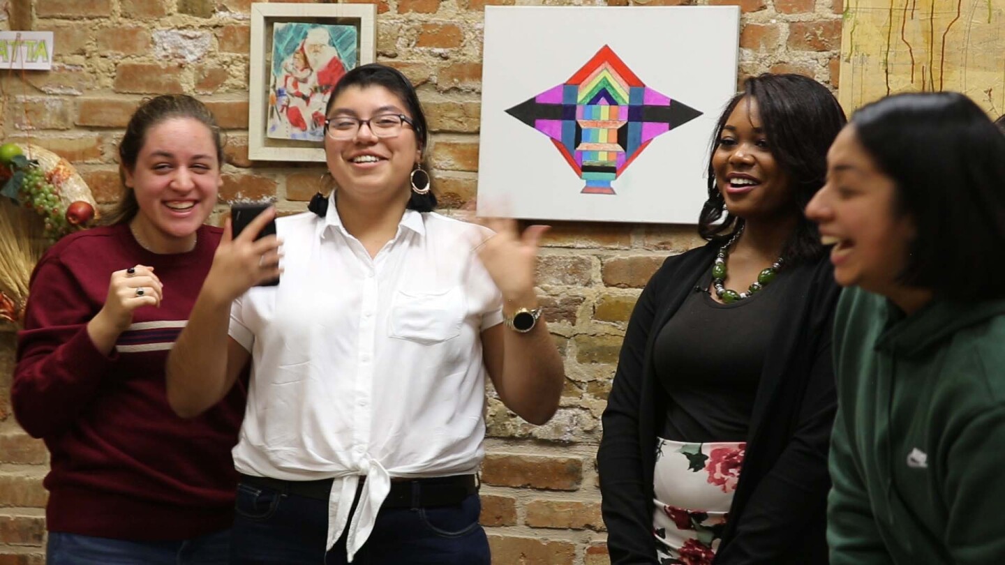 A group of four young women smiling. | Still from Global Mosaic