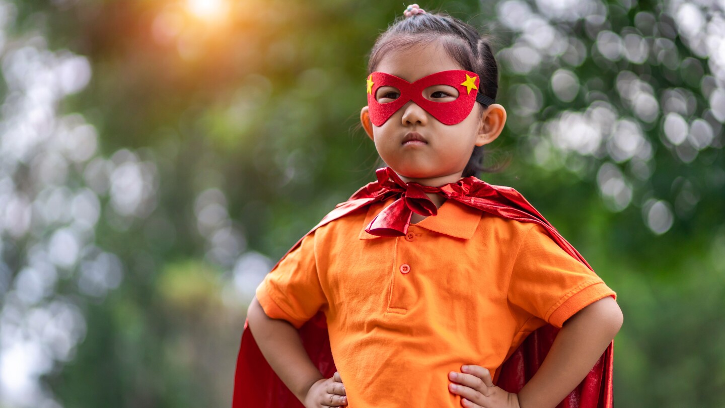 small Asian American child wearing a red mask and cape