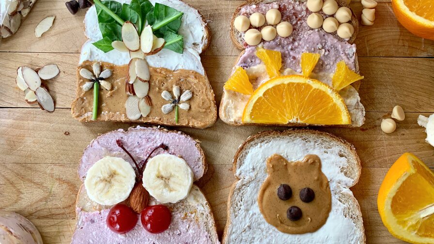 Four pieces of decorated toast featuring a palm tree, sunset, butterfly and teddy bear.