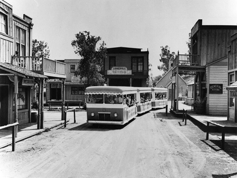 A tour bus moves through the backlot western sets of Universal Studios | Security Pacific National Bank Collection at Los Angeles Public Library