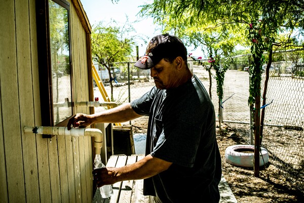 Roberto Mendez, a St. Anthony mobile home park resident and maintenance worker, fills his bottle at the on-site water station I Photo by Christian Mendez.