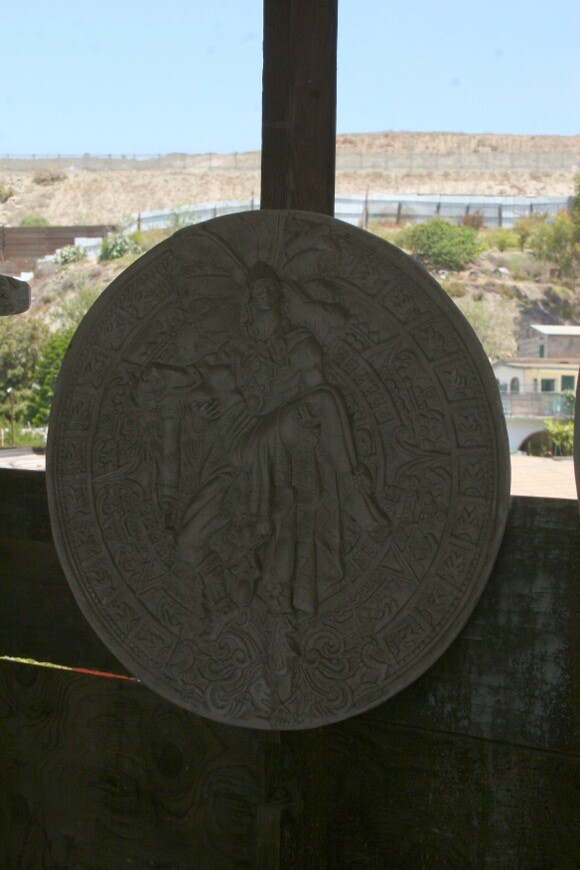Hanging relief sculpture in Oscar's workshop is a combination of Jesus Helguera Aztec imagery and the Aztec calendar. The dual border fence can be seen in the background. | Photo: Misael Diaz.