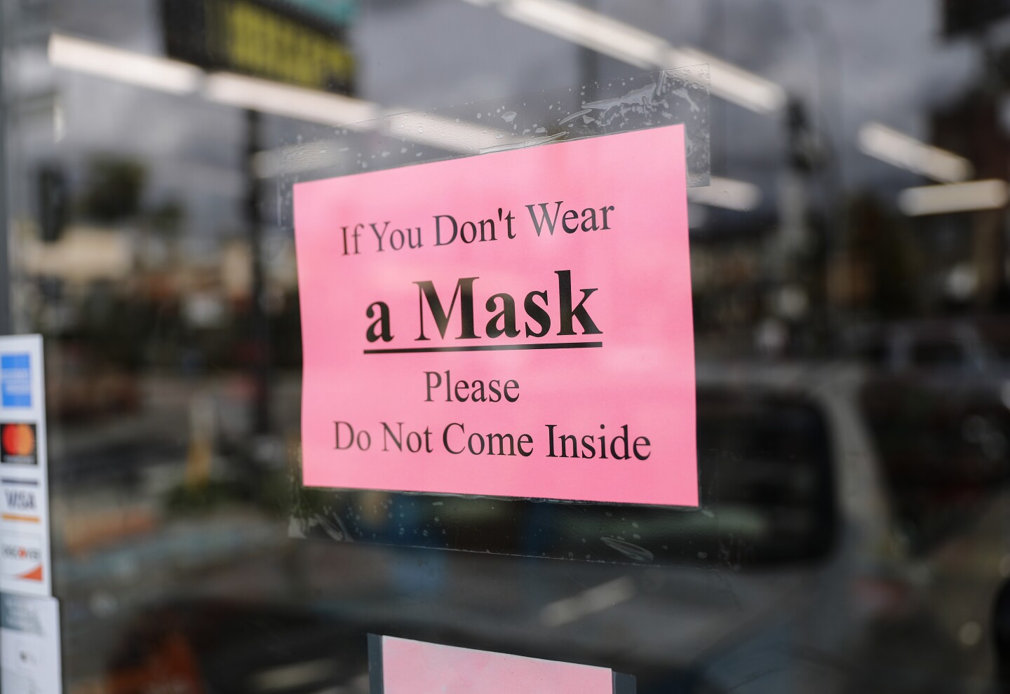 a pink sign on a door reads "If You Don't Wear a Mask Please Do Not Come Inside"