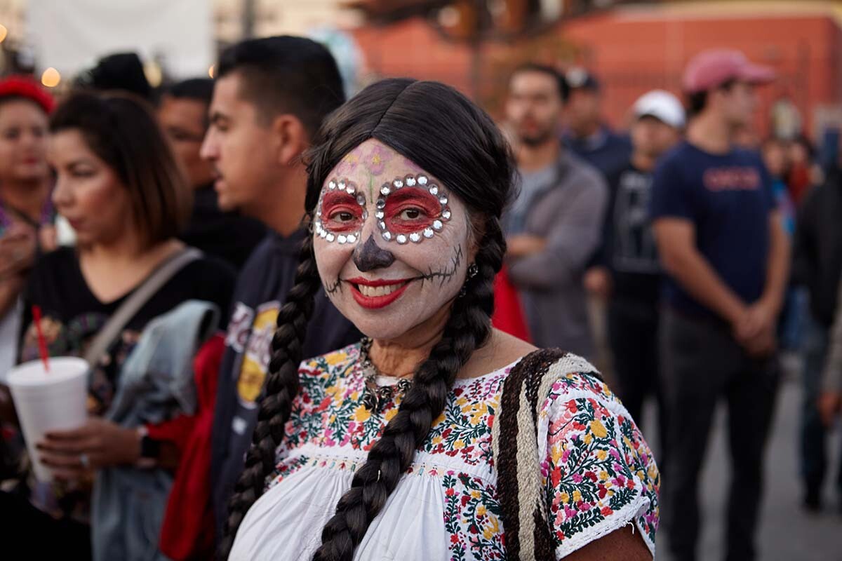 A young woman in calaveras paint smiles during the Día de los Muertos celebration in 2019 | Pablo Aguilar