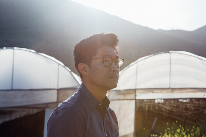 Aaron Choi stands in front of various greenhouses on his farm.