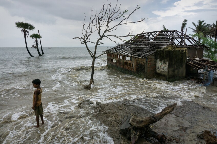 A boy stands near his home which his family had to abandon due to rising sea levels in West Bengal, India.