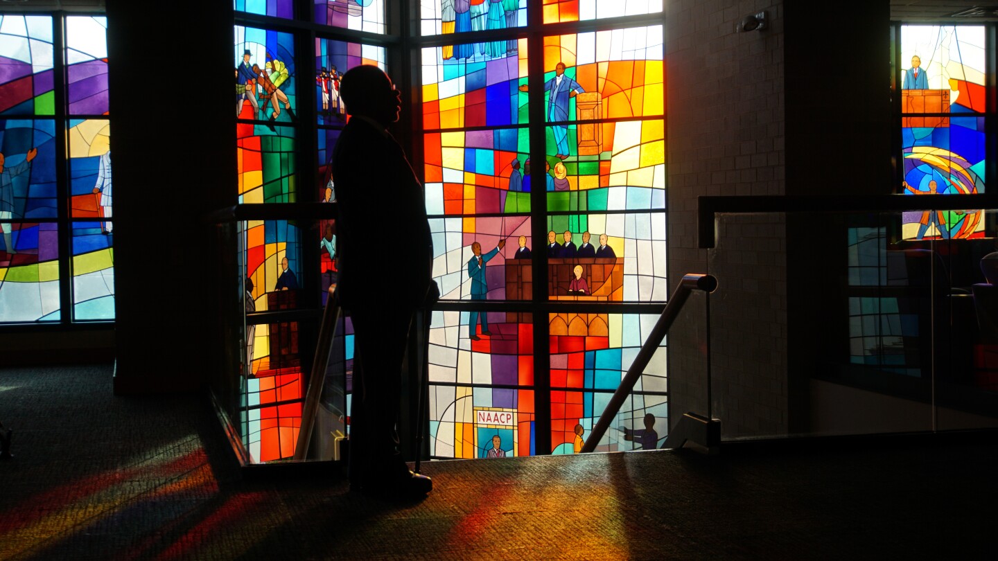 Host, Henry Louis Gates Jr. standing in front of stained glass at Trinity United Church of Christ in Chicago