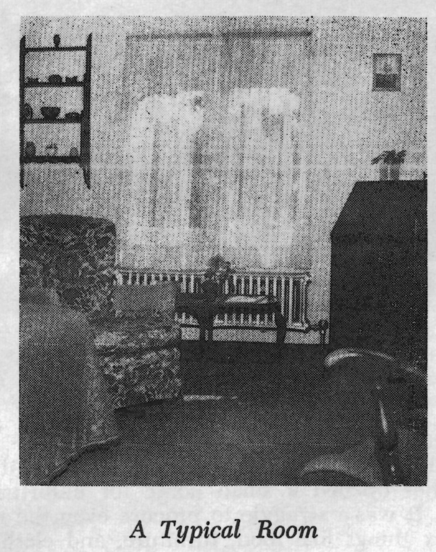 A black and white photo of a single room at the Woman's Christian Temperance Union Home. There is a floral arm chair, shelving with various items and a big window with sheer curtains.