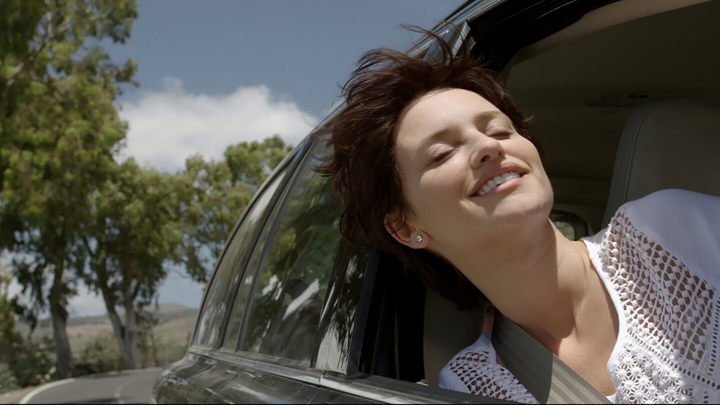 A woman sticks her head out of a car window and enjoys the breeze. | From "Ma Ma" / Kino Lorber
