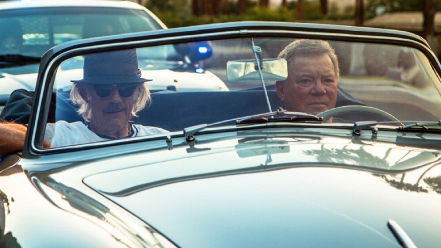 Two people riding in a top-down convertible.