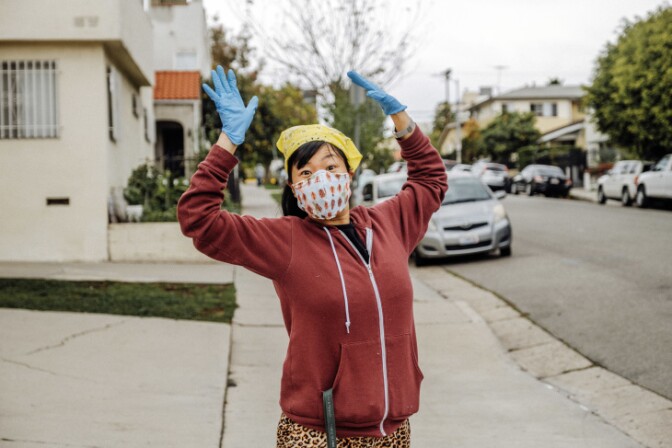 Kristina Wong smiles and rapidly waves her hands in the air. | Chava Sanchez/LAist