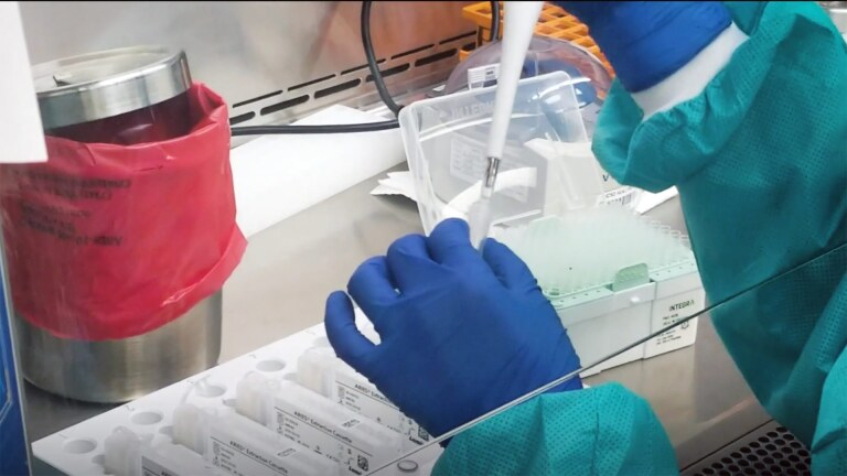 A lab worker inserts a sample into a container.