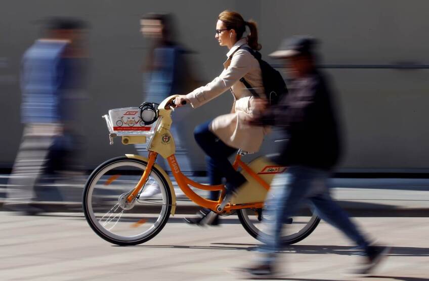 ARCHIVE PHOTO: A woman rides a bicycle from a bike-sharing service in downtown Milan, Italy, May 18, 2018. | REUTERS/Stefano Rellandini