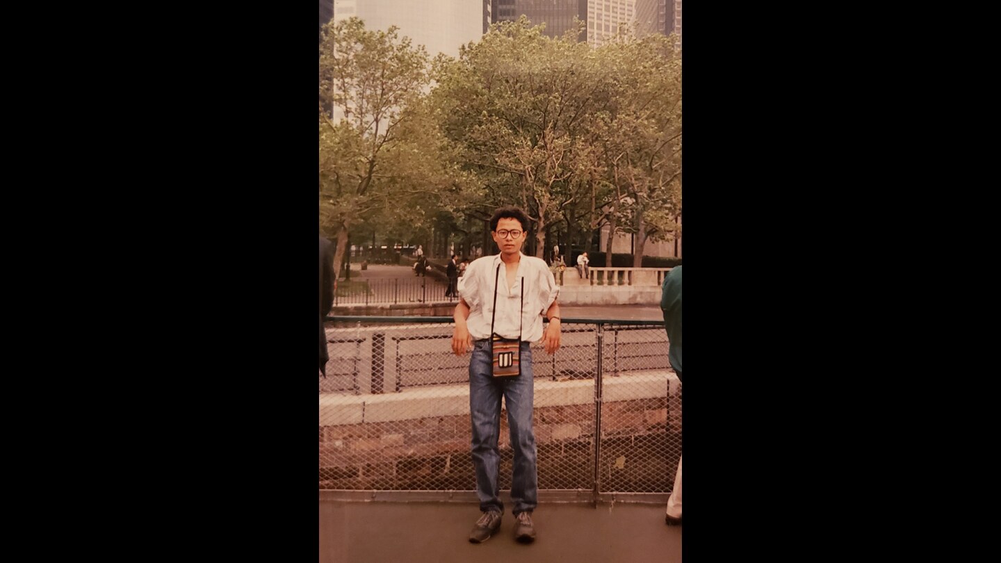 A man smiles while posing in front of a railing.