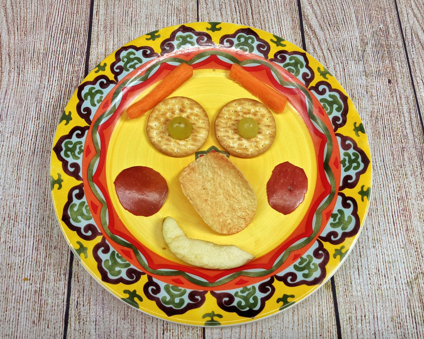 Una carita felíz hecha de comida sobre un plato amarillo.