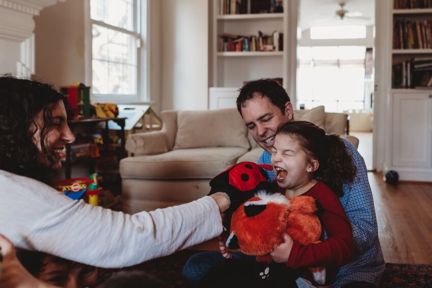 A young girl with a red shirt plays with her parents 