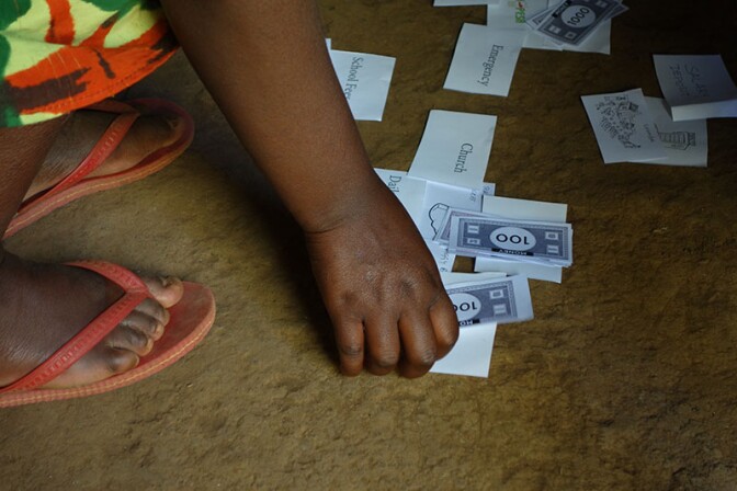 A young woman in Kenya demonstrates how she handles her finances using fake bills and flashcards. | Danny Alexander, IDEO.org