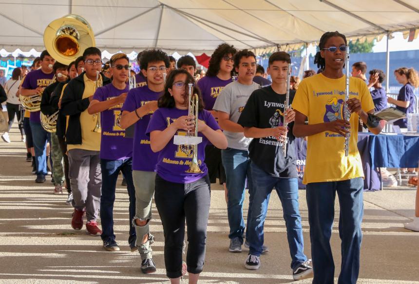 Young people with wind instruments march down in a parade.