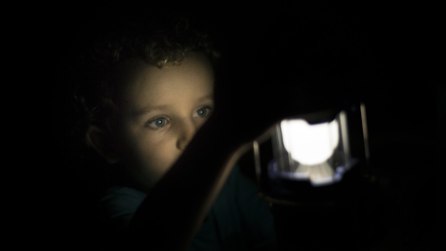 Boy playing with flashlight camping lamp on hideout