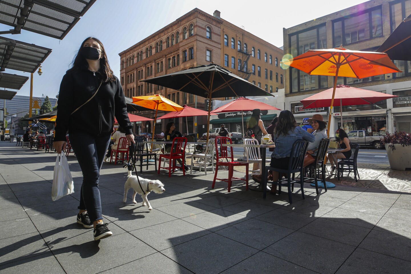 A woman with a dog walks by Grand Central Market on Tuesday, March 30, 2021 in Los Angeles , CA