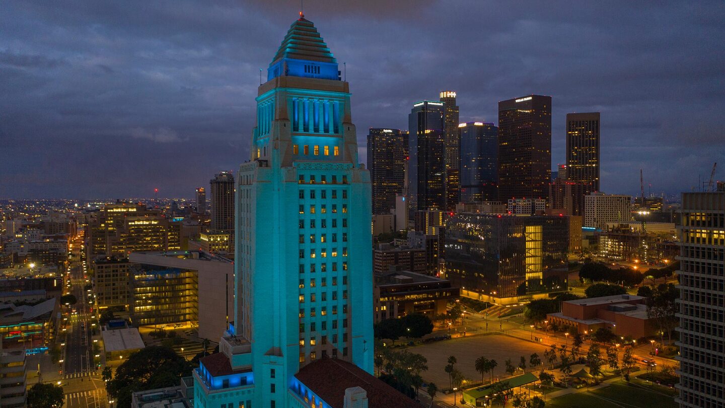 An aerial view shows Los Angeles City Hall illuminated in blue as a tribute to healthcare workers responding to the coronavirus pandemic on April 18, 2020 in Los Angeles, California.