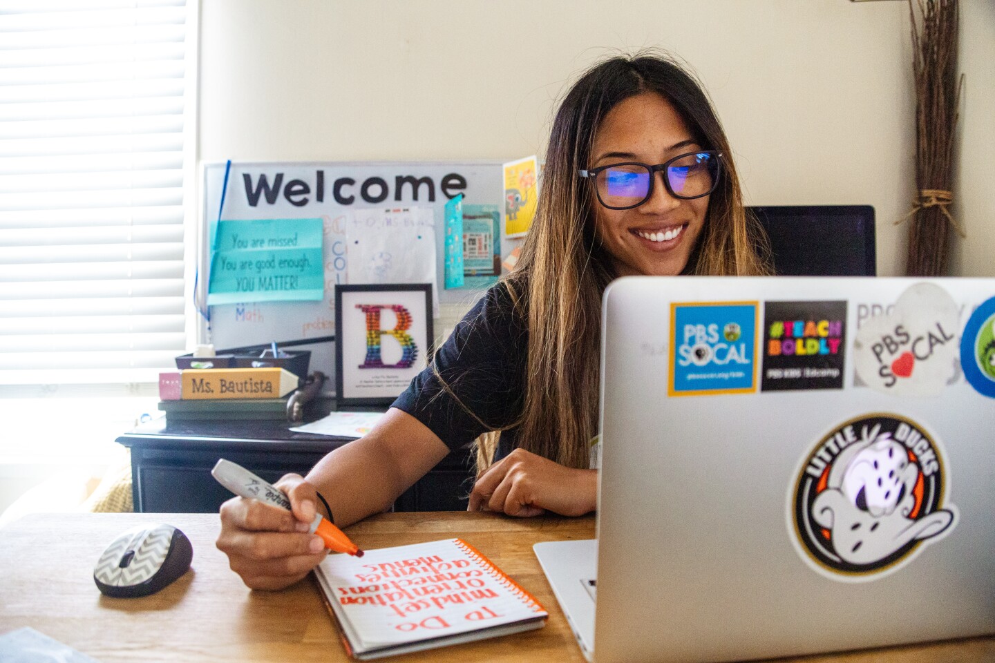 Teacher Shelly Bautista writes notes while interacting virtually.