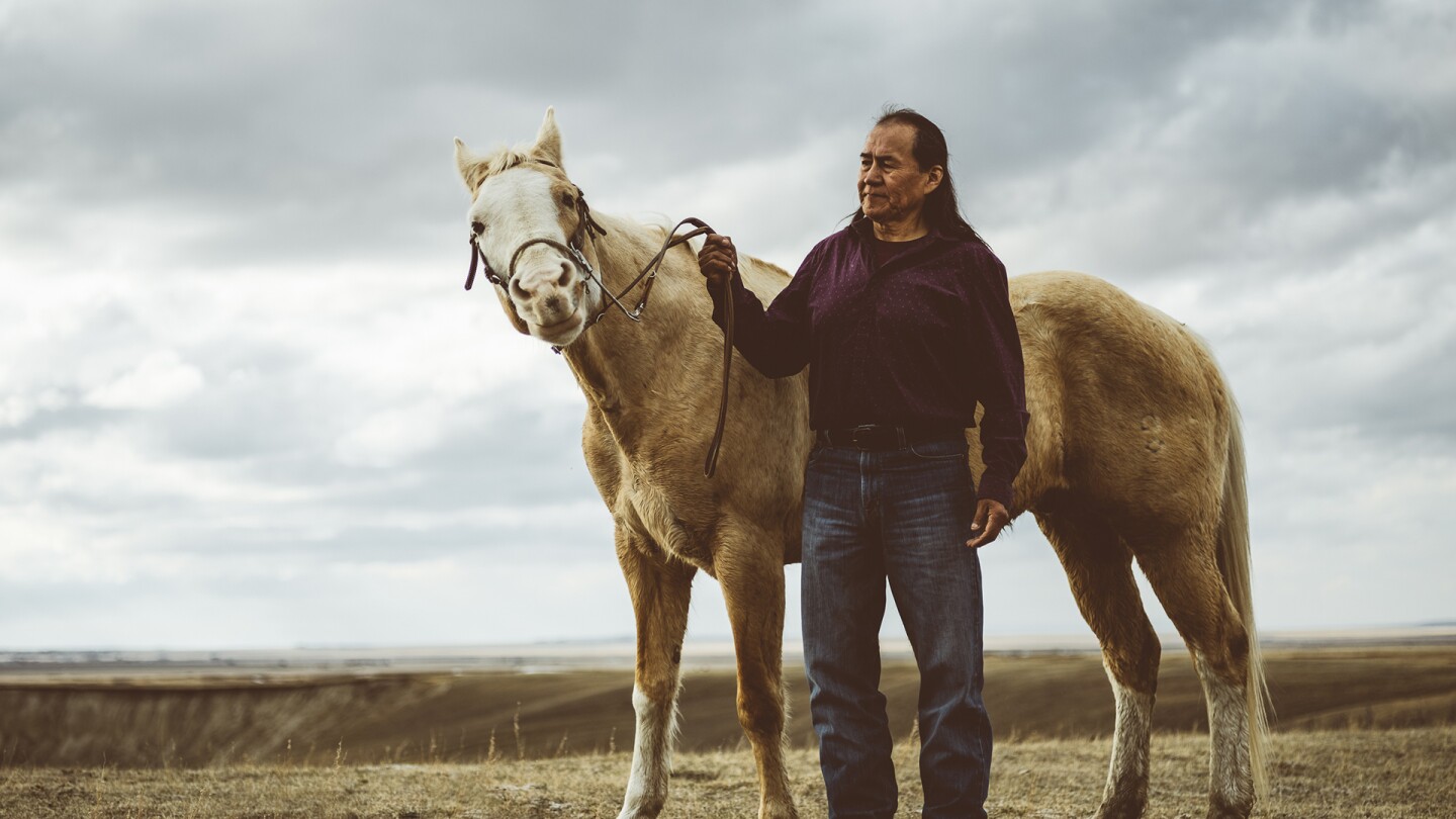 A man standing beside a horse, holding its reins in his hand.