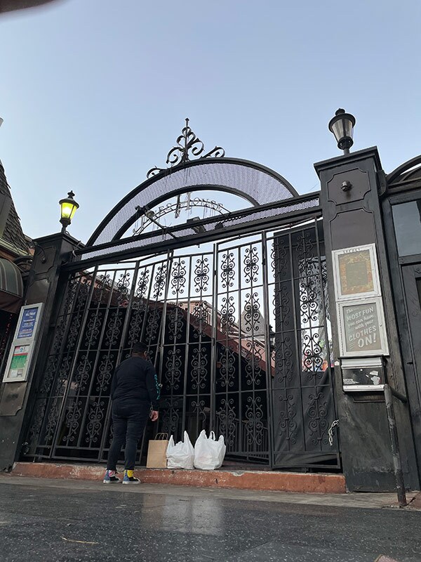 A person stands in front of white plastic bags, facing a gate.