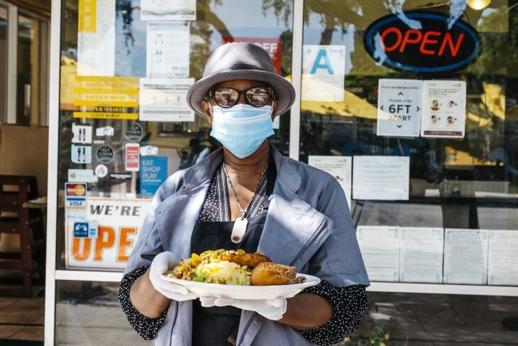 Marlene Beckford poses outside of Ackee Bamboo, holding one of her restaurant's signature dishes, ackee and saltfish.