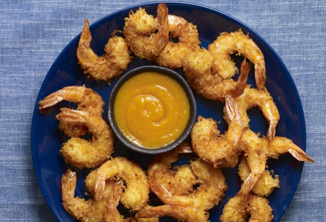 Coconut shrimp arranged on a blue plate with sauce in the middle. | From "Pati's Mexican Table: Season 5, Episode 5."