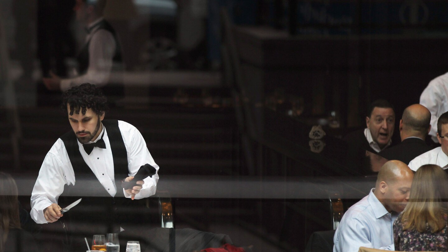 A waiter clears a table at a restaurant popular for business lunches on in New York City. | Spencer Platt/Getty Images