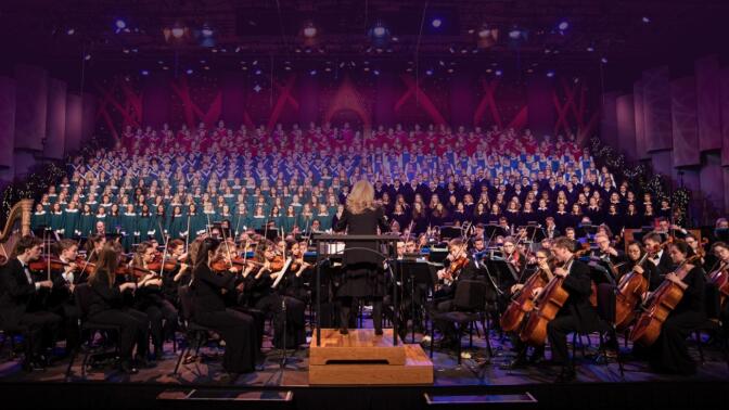 A conductor conducts an orchestra on stage.