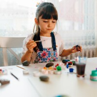 little girl is doing pattern rocks family math activity at home