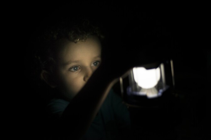 Boy playing with flashlight camping lamp on hideout