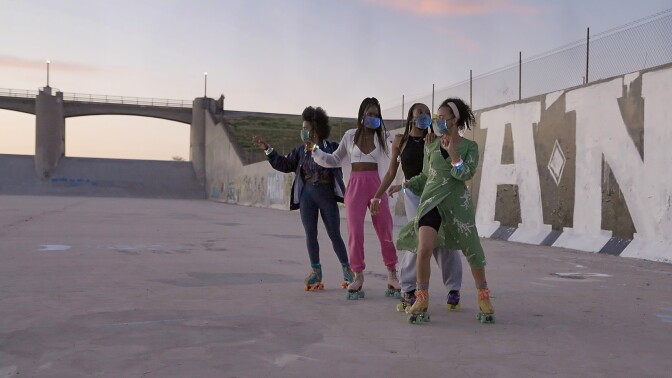 Four young women on roller skates wearing face masks at Sepulveda Dam.