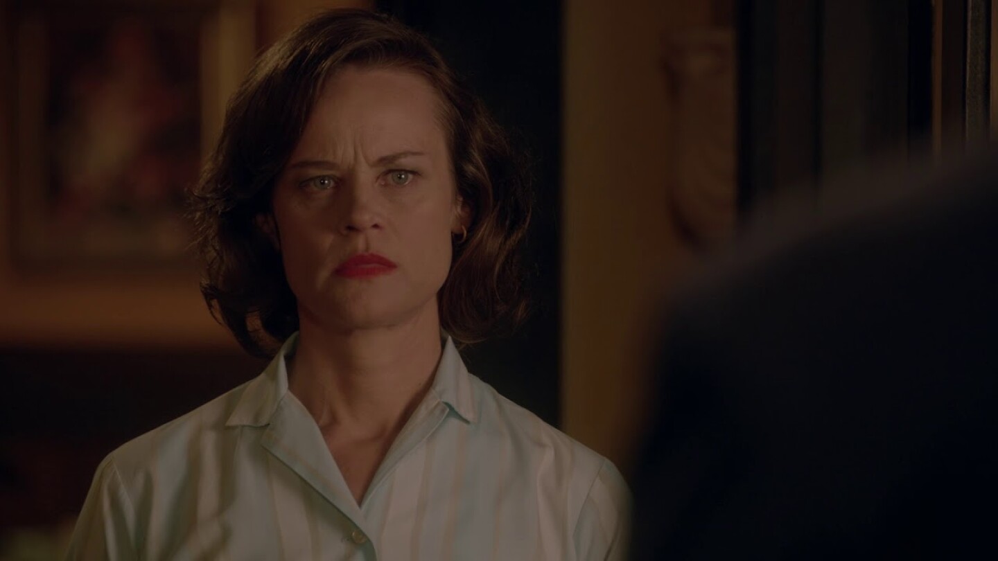 Nadine Garner wearing a light blue and white vertically striped button up shirt in a scene from The Doctor Blake Mysteries