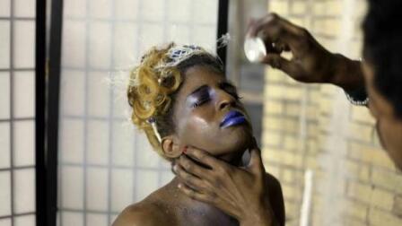 A person gets their makeup done by someone else.