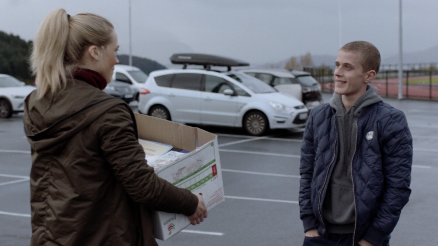 Helena talks to someone while holding a box from "Home Ground: The Great Escape."
