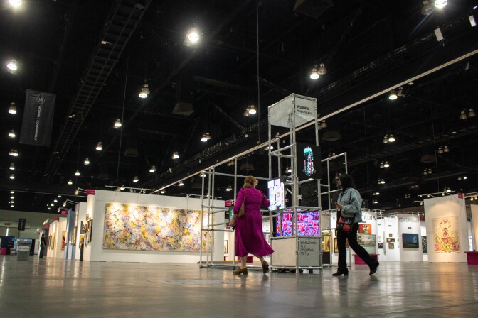 An exhibit displays various NFT-backed art pieces flashing on high-quality LED screens. The screens are mounted onto a metal pipe structure with metal sheet signs reading,