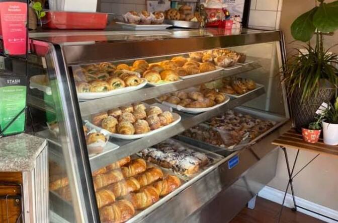 A variety of baked goods like croissants sit behind a glass container on display at a bakery.