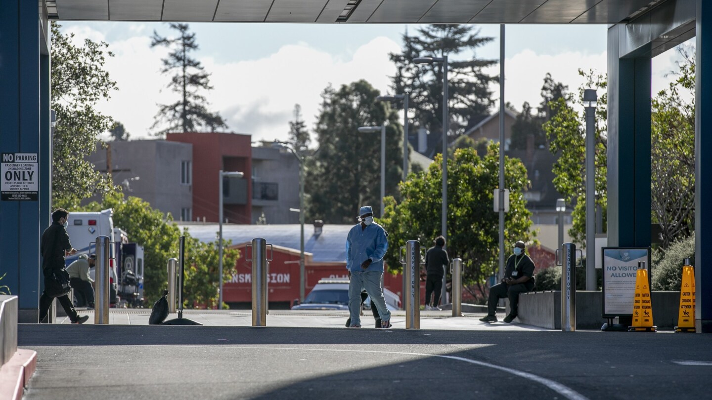 Patients and hospital staff wear masks outside of Kaiser Permanente Oakland Medical Center on Feb. 12, 2021.