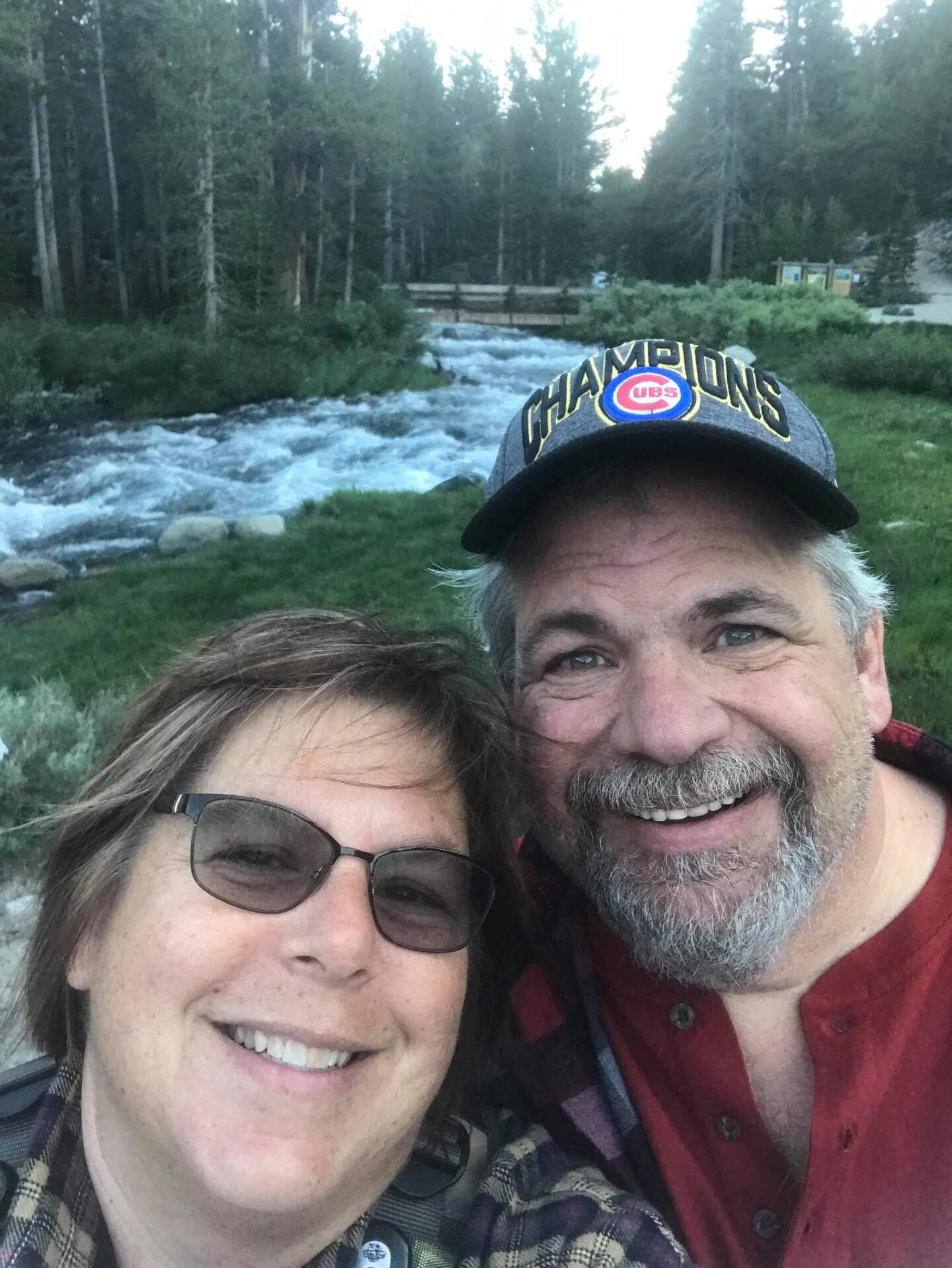 An older couple smile for the camera with a river in the background.