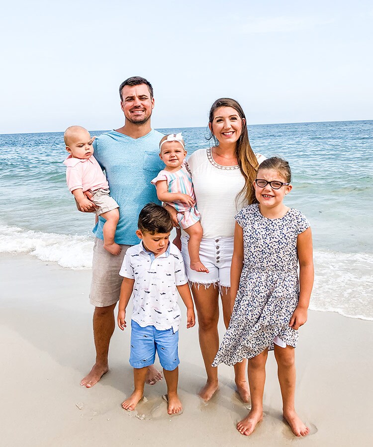 A white family stands together at the beach.