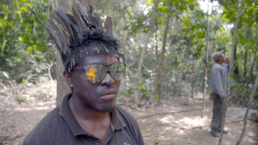 A guardian of Brazil's Amazon Rainforest watches as a fire burns the remains of lumber poachers. | Still from "Earth Focus"