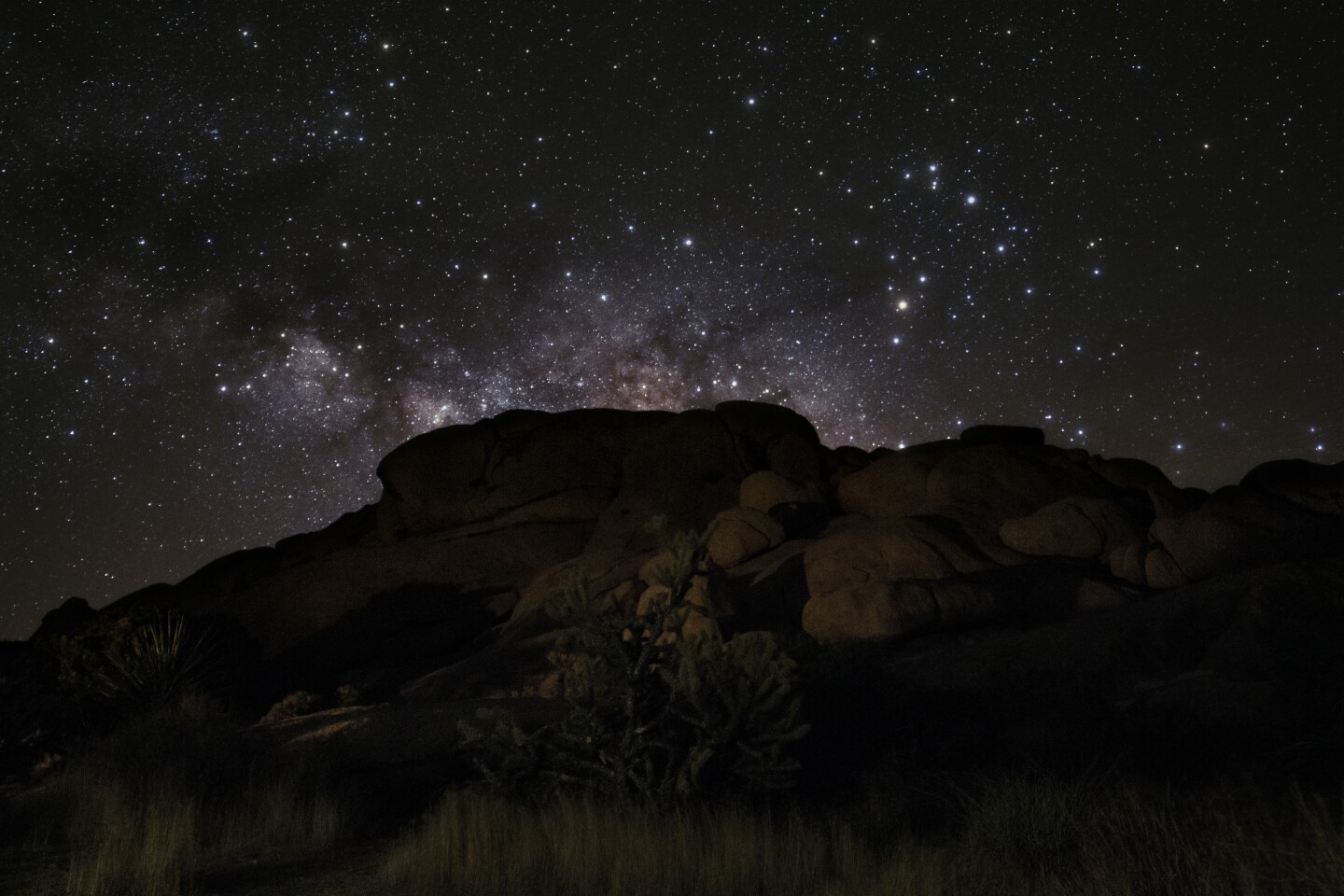 A night sky with a mountain in the foreground at Mojave National Preserve night skies.