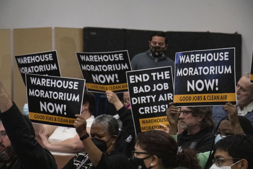 San Bernardino County residents raise signs in favor of the warehouse moratorium. Some "Warehouse Moratorium Now! Good Jobs & Clean Air" while another reads "End the Bad Job, Dirty Air Crisis!"