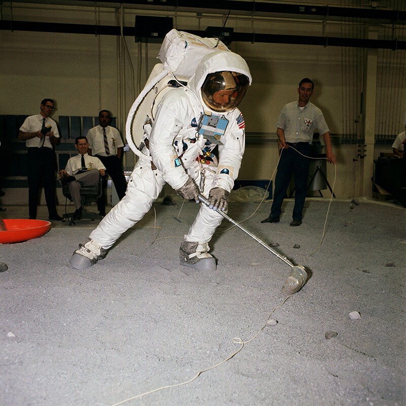 Astronaut Neil A. Armstrong, wearing an Extravehicular Mobility Unit (EMU), participates in lunar surface simulation training on April 18, 1969, in Building 9, Manned Spacecraft Center (now Johnson Space Center). In the months immediately before the Apollo 11 mission, the crew and the ground support teams had an intense schedule of training and simulation. Here, Armstrong practices scooping up a lunar sample. | Flickr/NASA/Creative Commons