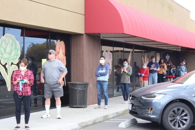 People standing in line at Trader Joes, some wearing face masks | Karen Foshay