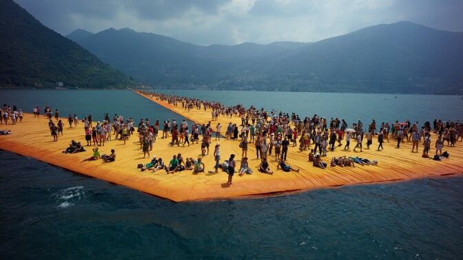 Hundreds of people stand on artist Christo's art installation "The Floating Piers," a yellow, three kilometer walkway, on Italy's Lake Iseo. | From "Walking on Water"